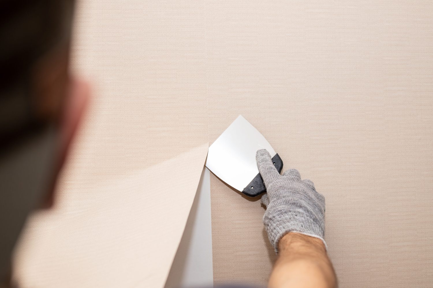 woman tears off Wallpaper, removing Wallpaper from the wall with a spatula, the process of updating the wall room repair.